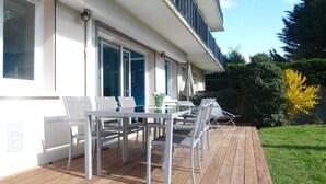 Eine Terrasse mit Tisch und Stühlen, einer Glastür und einer blauen Tür.