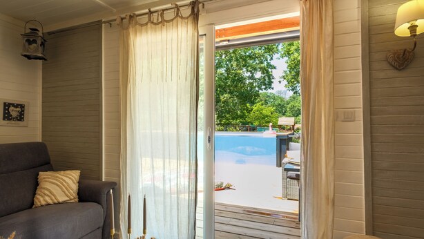 Una habitación con un sofá gris, una mesita redonda con velas y vista a una piscina exterior.