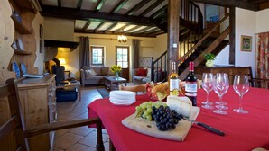A dining area with a red tablecloth, a wooden table, and a variety of food and drink items.