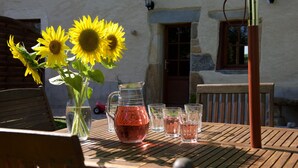 A wooden table with a pitcher of water, a vase with sunflowers, and several glasses.