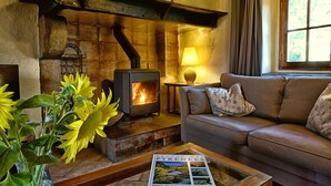 A cozy living room with a stone fireplace, a sofa, and a table with a magazine.