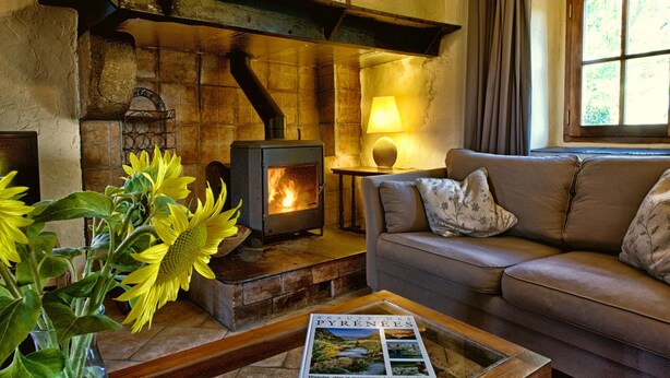 A cozy living room with a stone fireplace, a sofa, and a table with a magazine.