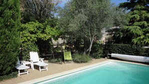 A swimming pool with two white lounge chairs and a green towel. - Charming house in Provencal Gard, large garden, swimming pool, children's games (Orsan)