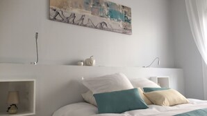 Un dormitorio moderno con una cama, almohadas, una mesita de noche y una obra de arte en la pared.
