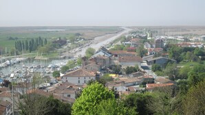 Eine Küstenstadt mit einem Yachthafen, Häusern mit roten Ziegeldächern und einem Fluss, der sich durch das Zentrum schlängelt.