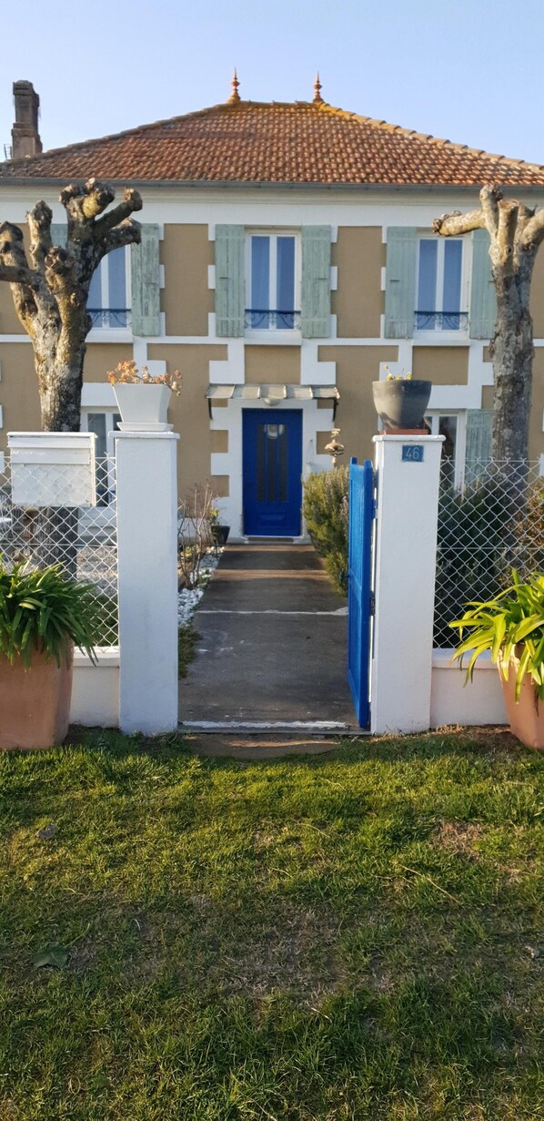 Ein Haus mit blauer Tür, weißen Säulen und einem Ziegeldach.