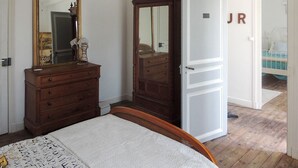 Ein Schlafzimmer mit einem hölzernen Bett, einem Schminktisch, einem Kleiderschrank und einem Spiegel.