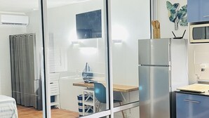 A modern kitchen with a refrigerator, microwave, and a dining area with a table and chairs. - Apartments in Saint-Francois (SAINT FRANCOIS)