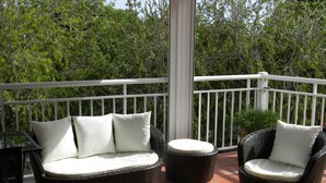 A balcony with wicker furniture, including a sofa and chairs, and a glass table. - Apartments in Saint-Francois (SAINT FRANCOIS)