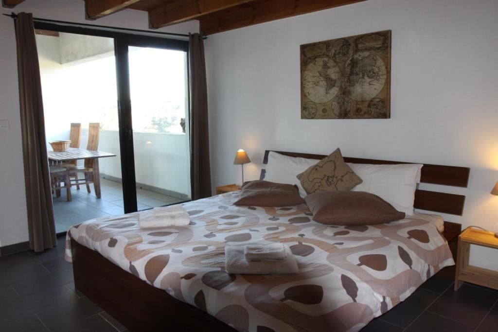 Een slaapkamer met een bed, een kaart aan de muur, een tafel met stoelen buiten en een schuifdeur.