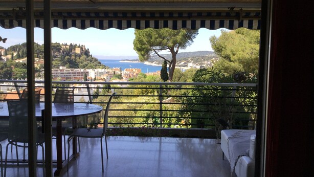 A balcony with a view of a coastal town, a table, and chairs. - A beautiful, quiet 3-star apartment in a wooded park with a view of the bay (Cassis)