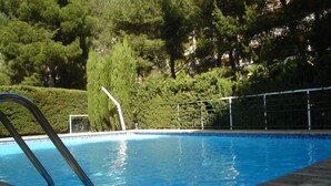 A swimming pool with clear blue water, surrounded by a metal fence and lush greenery. - A beautiful, quiet 3-star apartment in a wooded park with a view of the bay (Cassis)
