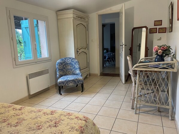 A bedroom with a bed, a blue patterned armchair, a dresser, a mirror, and a small table with a vase of flowers. - SANARY Small country house with garden. Small dogs accepted (Sanary-Sur-Mer)