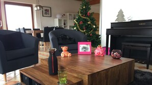 A living room with a wooden coffee table, a potted plant, a teddy bear, a framed photo, and a Christmas tree. - Bright architect-designed house-private saltwater pool-wonderful unobstructed view (Le Bugue)
