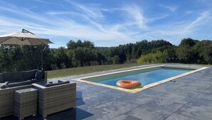 A rectangular swimming pool with a floating ring, surrounded by a paved deck. - Bright architect-designed house-private saltwater pool-wonderful unobstructed view (Le Bugue)