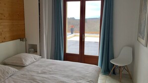 A bedroom with a bed, a chair, and a view through a glass door. - Bright architect-designed house-private saltwater pool-wonderful unobstructed view (Le Bugue)