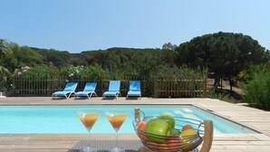 Zona de piscina con sillones de descanso, un frutero y dos copas de martini.