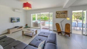 Una sala de estar moderna con un sofá gris, una mesa de centro, un televisor y una lámpara colgante roja.