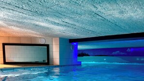 An indoor swimming pool with a tiled floor, a large mirror, and a blue-lit wall. - House with private indoor pool and 29° sauna. Summer 2027: Private Indoor and Outdoor Pools (Boqueho)