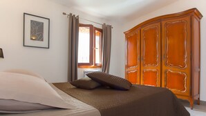 A bedroom with a bed, a wardrobe, a window with curtains, and a framed picture on the wall. - MONTE-CINTO Stone house -PAGLIAGHJU- Gorges de l'Asco, not far from the sea  (Moltifao)