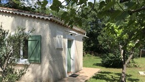 A small, rustic building with a tiled roof and green shutters, surrounded by a well-maintained garden and trees. - Villa with swimming pool, large terrace, all comfort, enclosed garden, calm. (Forcalqueiret)