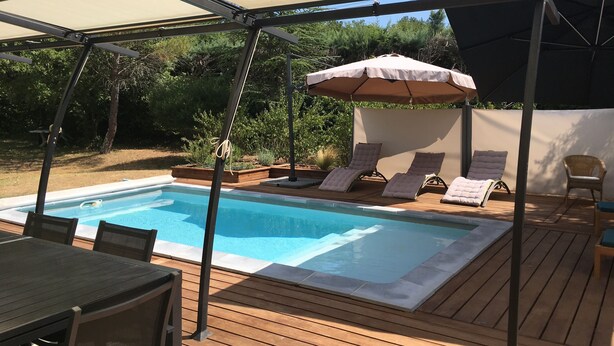 A pool area with a covered deck, lounge chairs, and a table. - Villa with swimming pool, large terrace, all comfort, enclosed garden, calm. (Forcalqueiret)