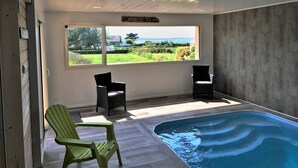 Een kamer met uitzicht op een landschap, twee stoelen en een zwembad.