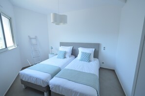 Une chambre avec deux lits, une échelle et un luminaire suspendu.