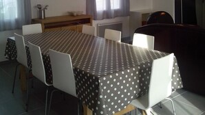 A dining area with a table set for four, two pendant lights, a window with curtains, and a radiator.