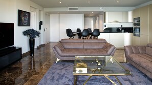 Un salon moderne avec un canapé en cuir marron, une table basse en verre et un téléviseur à écran plat.
