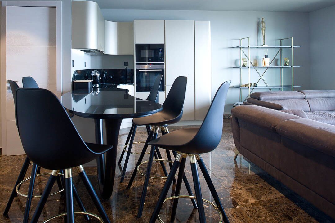 A modern kitchen with white cabinets, a black dining table, and matching chairs.