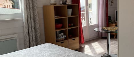 A bedroom with a bed, a wooden cabinet, and a desk with a chair.
