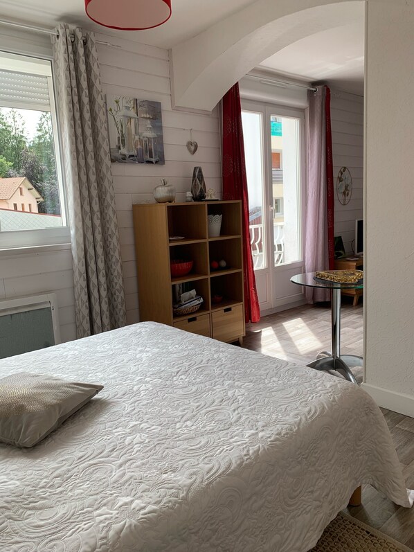 A bedroom with a bed, a wooden cabinet, and a desk with a chair.