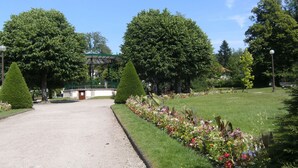 A park with a gazebo, neatly trimmed hedges, and a variety of flowers.