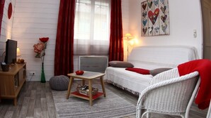 A cozy room with a bed, a small table, a chair, a desk, and a radiator.