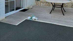 A patio with a table and chairs, a stone wall, and a door with blue shutters. - 3-STAR HOUSE IN LA COTINIERE, 50 M FROM THE FISHING PORT (saint pierre d oleron)