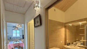 A hallway leading to a bathroom with a sink and mirror, a dining area with a table and chairs, and a kitchen visible in the background. - 3-STAR HOUSE IN LA COTINIERE, 50 M FROM THE FISHING PORT (saint pierre d oleron)