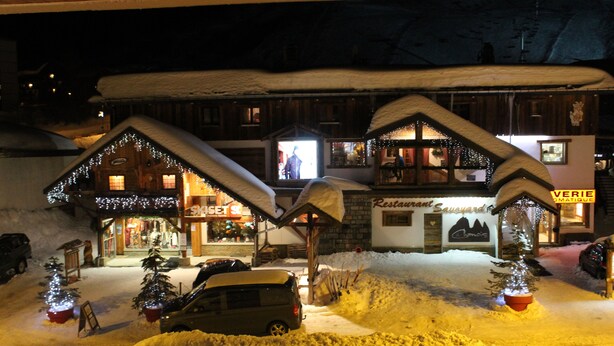 Un edificio cubierto de nieve con restaurante y una tienda de esquí.