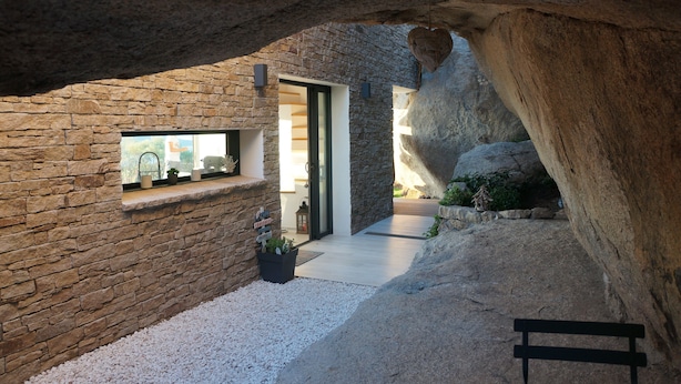 A stone-walled interior with a wooden bench, a small window with plants, and a pathway leading to a door. - Stone house with panoramic views over the bay of Figari, outdoor spa (Pianottoli-Caldarello)