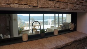 A stone-framed window with a view of a dining area, a plant, and a decorative item on the windowsill. - Stone house with panoramic views over the bay of Figari, outdoor spa (Pianottoli-Caldarello)