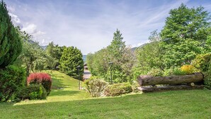 A well-maintained garden with a variety of trees and shrubs, a grassy lawn, and a large log. - 3 room apartment  (Megève)