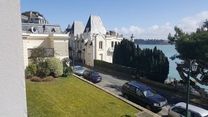 A residential street with a row of houses, a parked car, and a view of the sea.