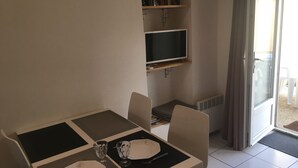 Ein Essbereich mit Tisch für zwei Personen, einer Bücherwand und einem Fernseher.