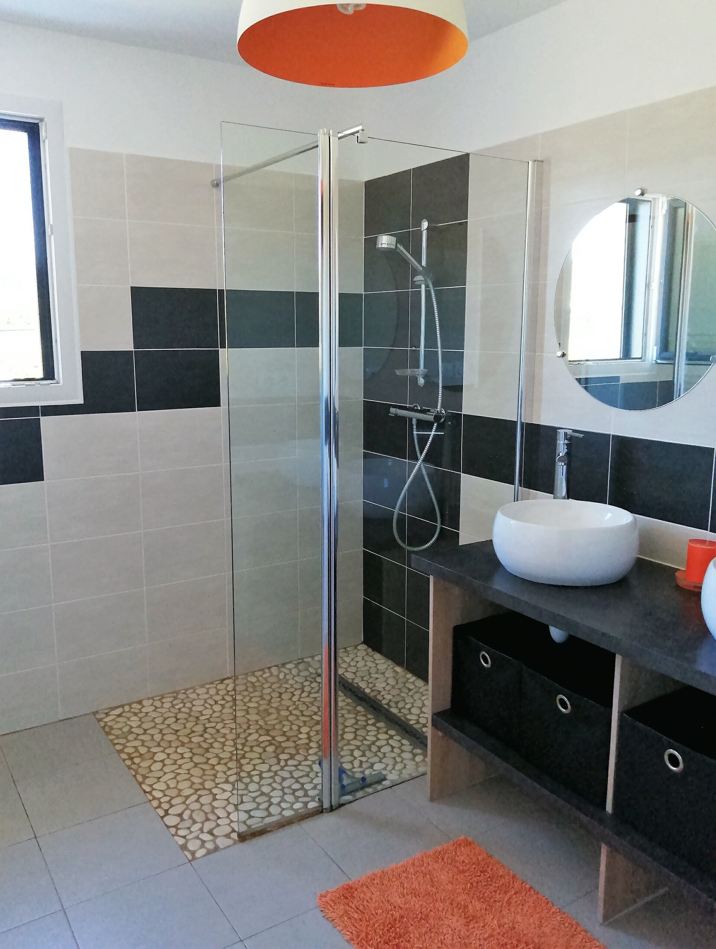Un baño moderno con ducha de vidrio, un lavabo blanco y un espejo encima.