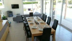 A modern dining area with a long wooden table set for six, surrounded by black chairs. - Modern villa in Les Sables d'Or with heated pool (Plurien)