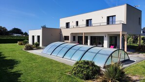 A modern two-story house with a covered outdoor area and a well-maintained lawn. - Modern villa in Les Sables d'Or with heated pool (Plurien)