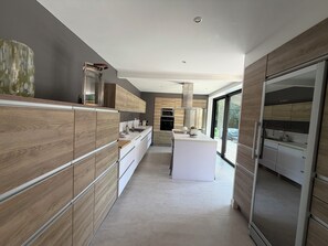 Una cocina moderna con armarios de madera, una isla central y un gran ventanal con vistas.