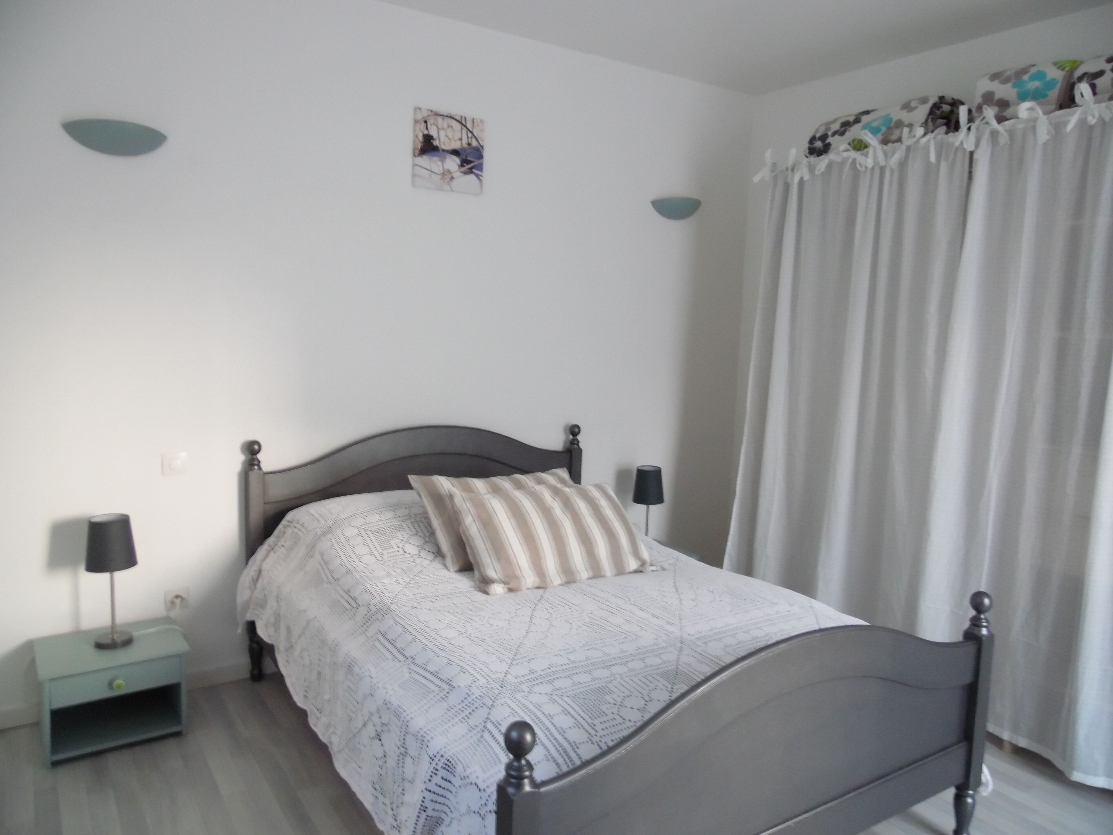 A bedroom with a bed, nightstands, a lamp, and a window with curtains.
