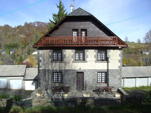 A two-story stone building with a balcony, multiple windows, and a front entrance.