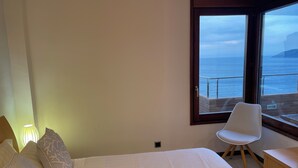 A bedroom with a bed, a chair, and a view of the sea through a window. - Luxury penthouse with terrace and jaquzzi the panoramic sea views (LLANÇA)